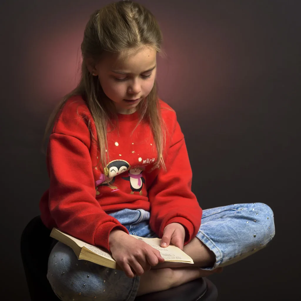 Nastya Photo Shoot-7327 A young girl reading a book in a studio setting captured by Dick Lloyd Photography