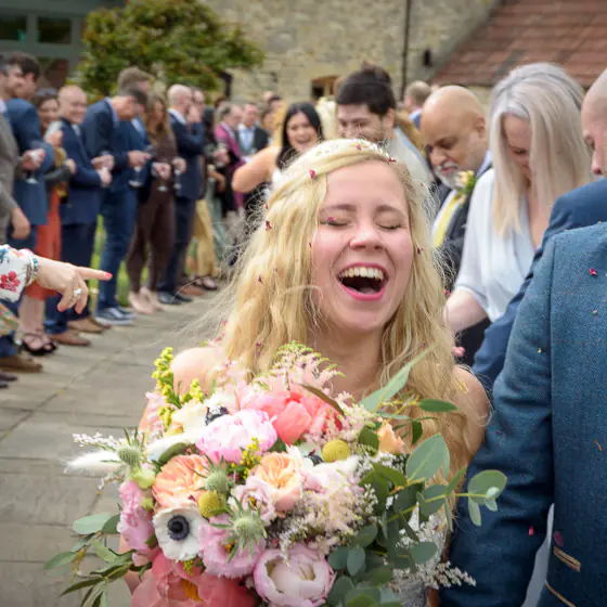 Bride laughing joyfully during confetti walk at a countryside wedding near Bath, candid wedding photography by Dick Lloyd