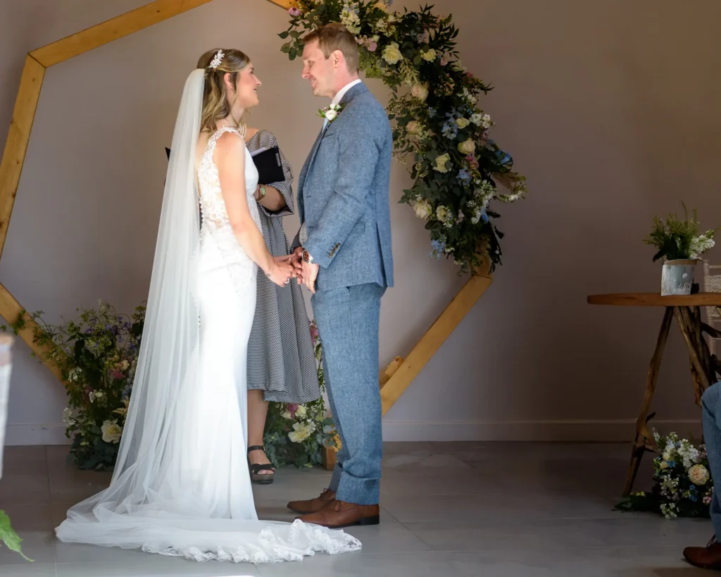 Forever Moments Collection – Wedding Ceremony Photography Bride and groom holding hands during their wedding ceremony, captured by Dick Lloyd Photography, a Yorkshire wedding photographer.