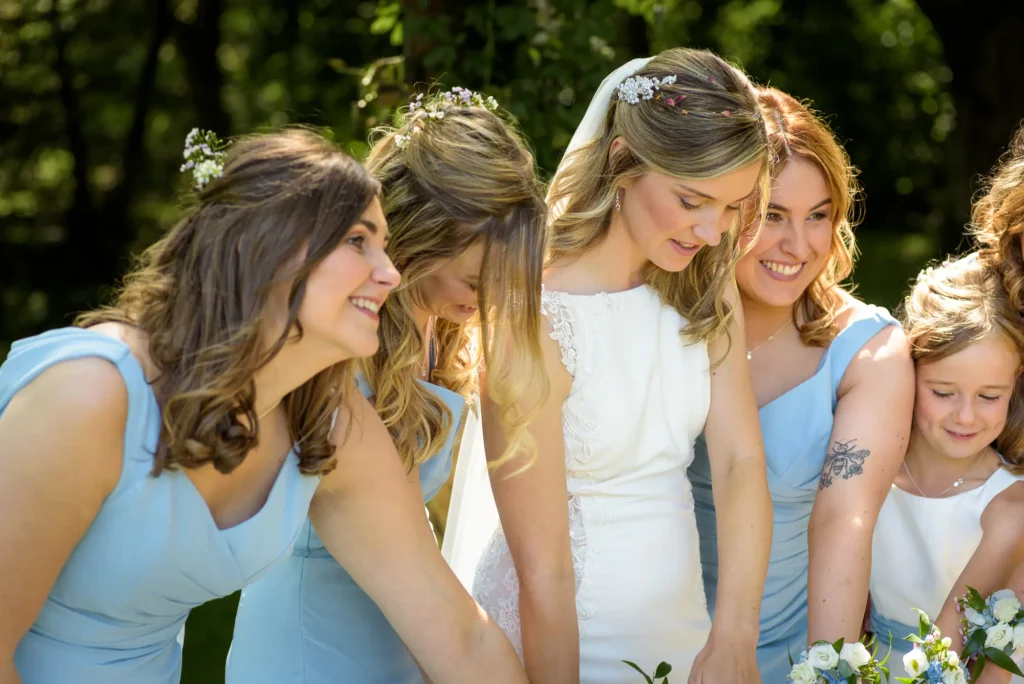 Angharad & Lewis Wedding-1171 Bride surrounded by bridesmaids in blue dresses, sharing a joyful candid moment during Pembrokeshire wedding photography by Dick Lloyd Photography