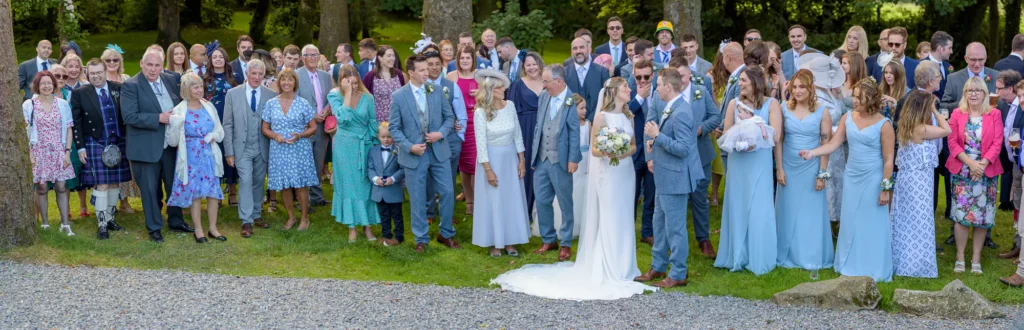 Angharad & Lewis Wedding-1232-Pano Wide angled view of the couple with all of their wedding guests, captured by Dick Lloyd Photography
