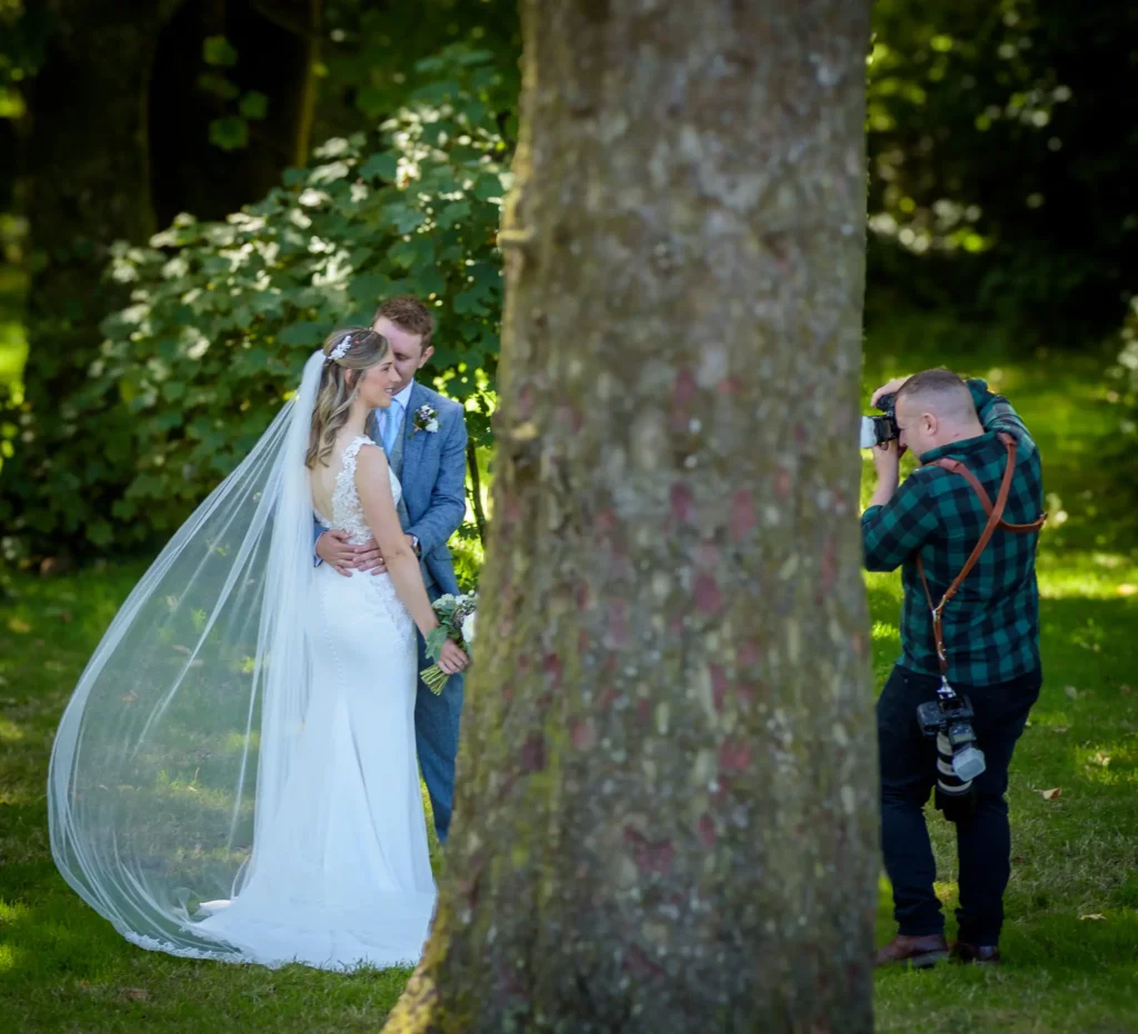 Angharad & Lewis Wedding-1265 Bride and groom sharing a quiet moment behind a tree, captured during Pembrokeshire wedding photography by Dick Lloyd Photography.