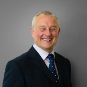 Smiling businessman in suit - headshot with grey background