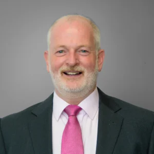 Businessman wearing dark suit with bright pink tie - headshot with grey background