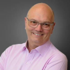 Businessman wearing glasses in pink shirt - corporate headshot with grey background
